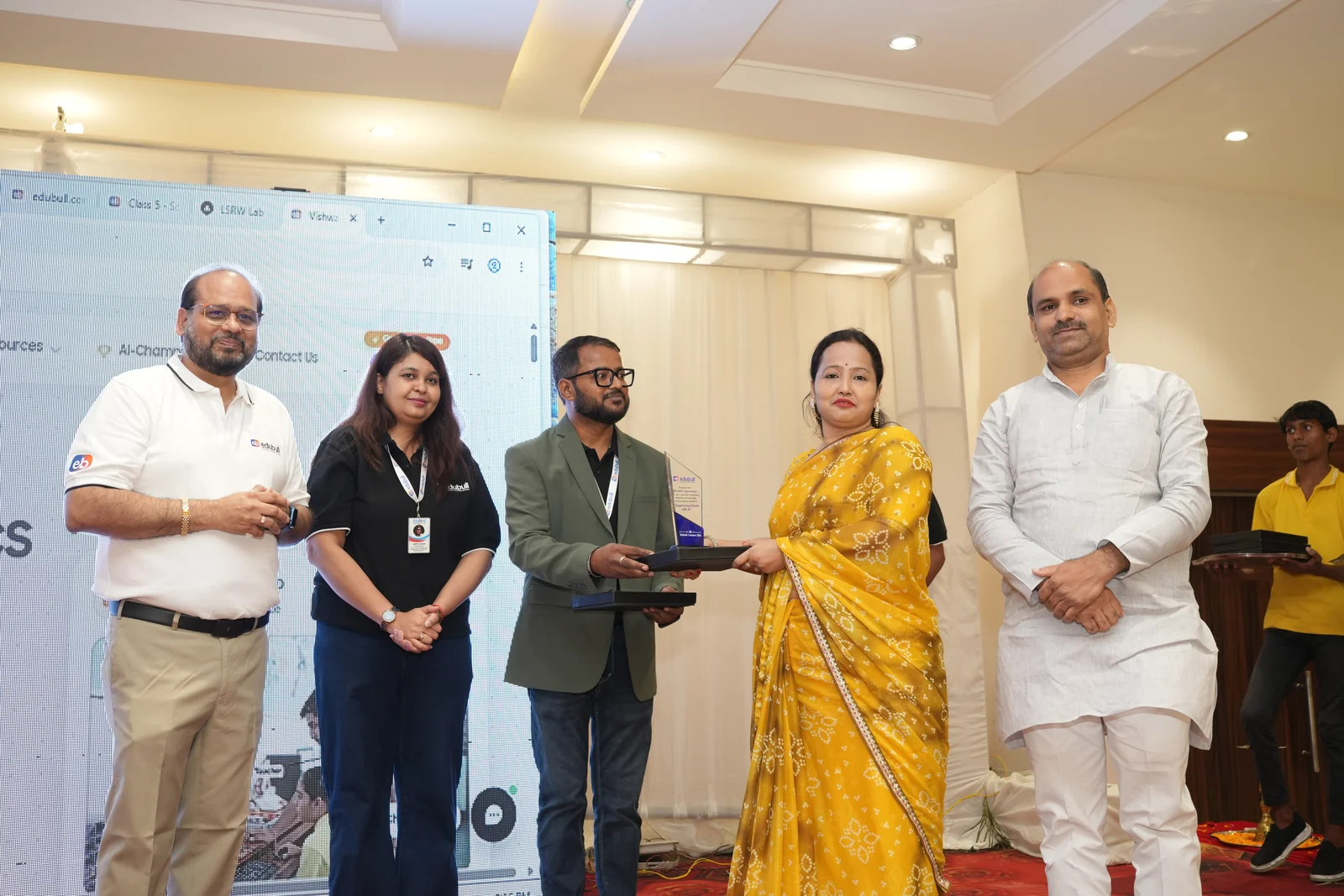 School director receiving award on stage with smart panel display in background