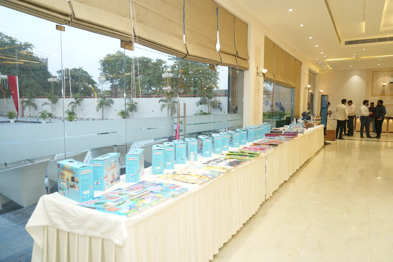 Long banquet exhibition table displaying AI textbooks, robotics kits, and panel bundles