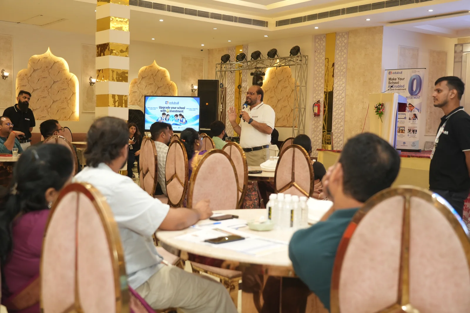 Girish Sharma addressing school directors and principals at the Azamgarh Conclave with the Zero Investment AI roadmap on display