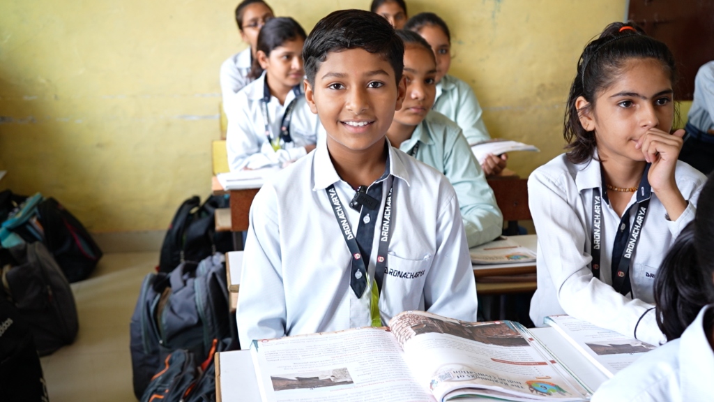 Smiling student studying with open hybrid textbook in class