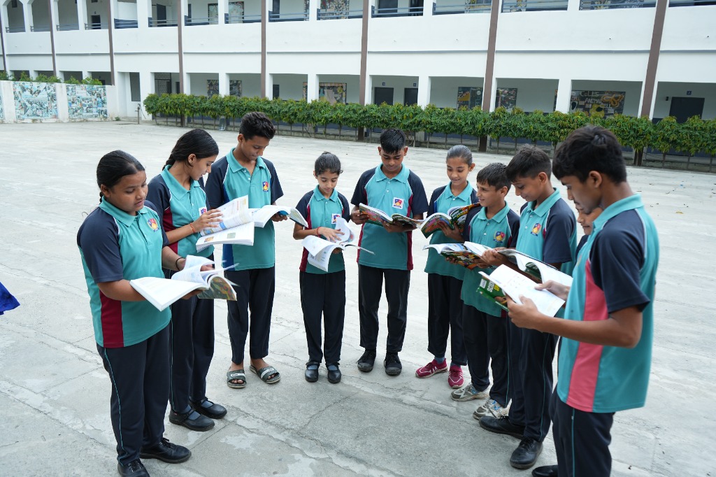 Group of school students reading hybrid textbooks outdoors together